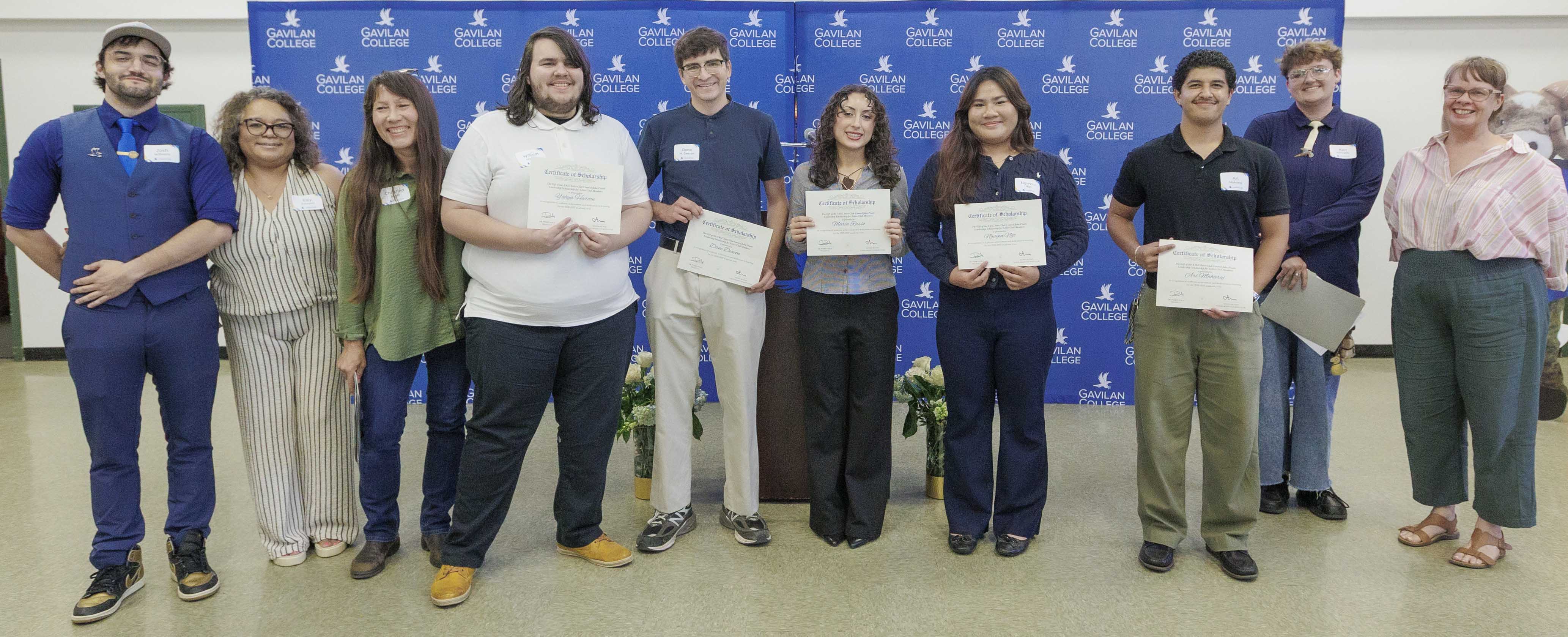 A group of scholarship recipients and college staff pose for a photo in front of a Gavilan College backdrop. Several students hold scholarship certificates.