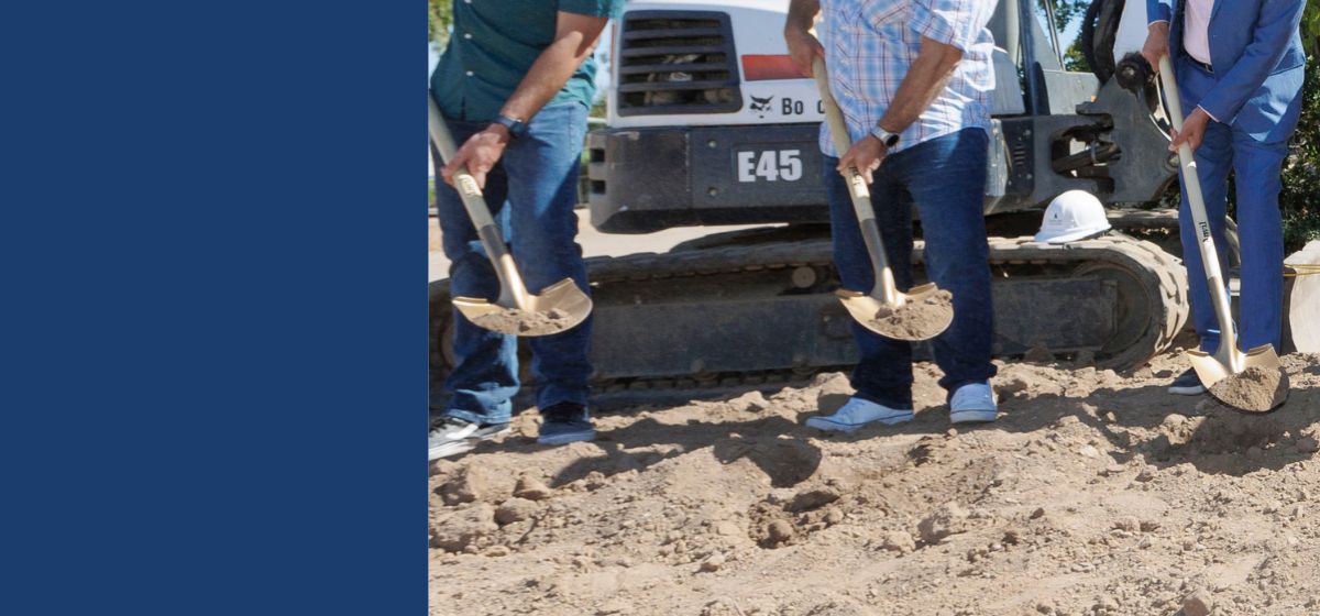 photo of legs of three individuals with dirt on three shovels at a groundbreaking
